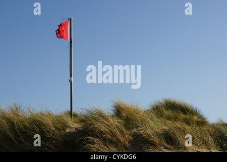 Rote Warnflagge auf einem Strand, die Badegäste darauf hinweist, dass es so ist Es ist gefährlich, am Strand von Fairbourne in Wales zu baden oder zu schwimmen Stockfoto