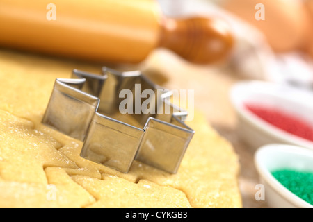 Weihnachtsplätzchen Backen: Ausstecher auf Zucker oder Butter Cookie-Teig mit Nudelholz hinten ausgerollt Stockfoto