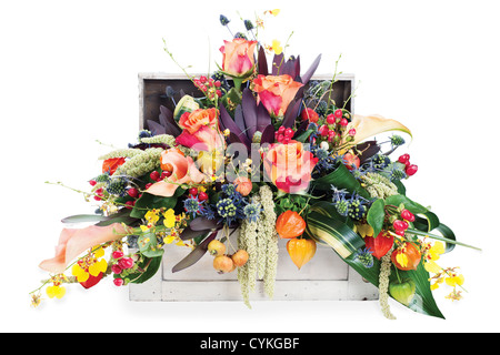 buntes Blumengesteck mit Rosen, Lilien, Freesien und Iris in eine hölzerne Truhe, isoliert auf weißem Hintergrund Stockfoto