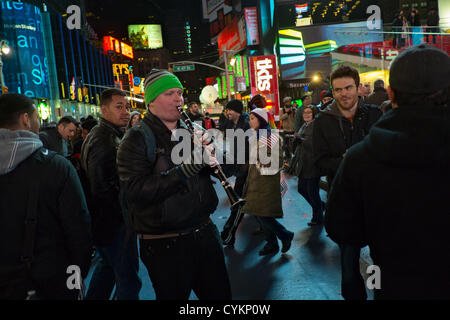 7. November 2012, New York, NY, USA.  Nach Präsident Barack Obama Siegesrede spielt einen Mann auf dem Times Square "We Shall Overcome" auf der Klarinette als Menge am Times Square Obamas Wiederwahl Sieg in den USA Präsidentschaftswahlen 2012 feiert. Stockfoto