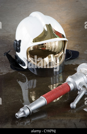 Einen Helm und eine Düse auf dem Boden in eine Firestation verwendet durch die Feuerwehr Stockfoto