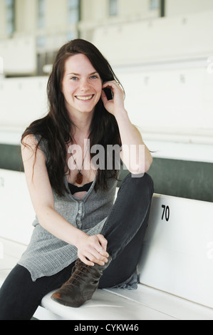 Lächelnde Frau sitzen auf Bank Stockfoto