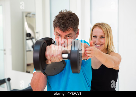 Trainer, die Anpassung des Mannes Form im Fitness-Studio Stockfoto