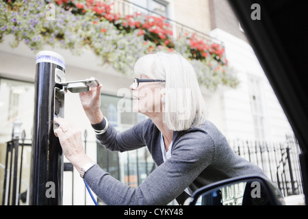 Frau Elektroauto auf Straße laden Stockfoto