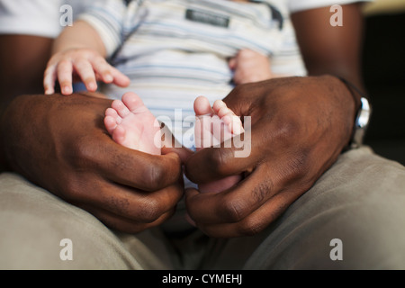 Vater hält die kleinen Füße Babys Stockfoto