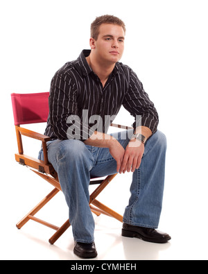 Lässige junge Mann sitzt im Regiestuhl. Stockfoto