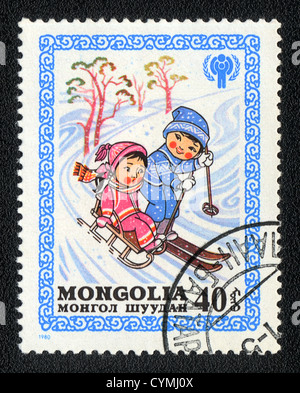 Eine Briefmarke gedruckt in der Mongolei zeigt jungen und Mädchen Folie nach unten auf Schlitten und Skier, aus Serie glückliche Kindheit, ca. 1980 Stockfoto