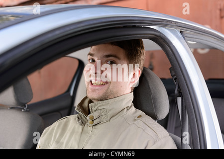 Glücklich Jüngling sitzt lächelnd in seinem Auto Stockfoto