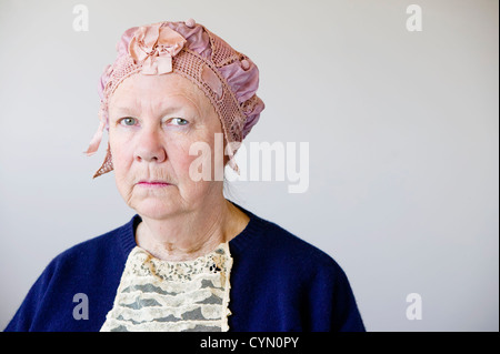 Mürrischen senior Frau im Studio mit einem Vintage Hut und Spitze. Stockfoto