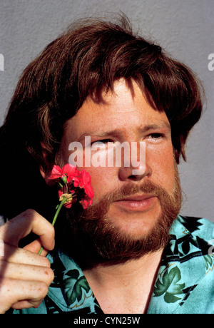 Ein junger Hippie Mann mit langen Haaren, Bart und Blumen fotografiert wurde 1967 in San Francisco, Kalifornien, USA. Stockfoto