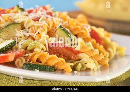 Bunte Fusilli Nudeln mit Zucchini, Tomaten und geriebenem Käse (selektiven Fokus, Fokus auf die Tomate vor) Stockfoto