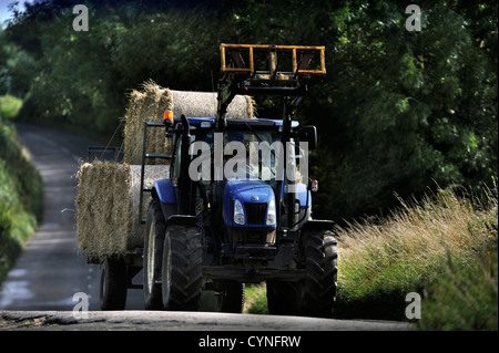 Ein Traktor zieht einen Anhänger von Heuballen in Gloucestershire UK Stockfoto