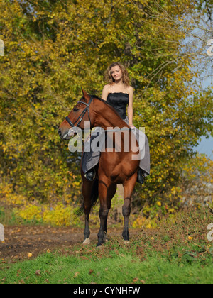 Cowgirl in Vintage-Kleid auf einem Pferd sitzend Stockfoto