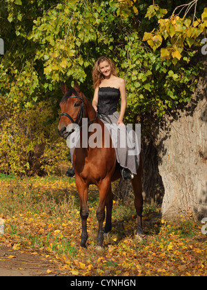 Cowgirl in Vintage-Kleid auf einem Pferd sitzend Stockfoto