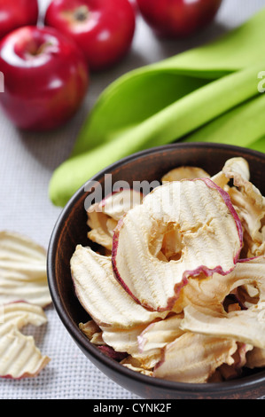 Getrocknete Äpfel Chips in Keramikschale mit frischen roten Äpfeln auf Tisch Stockfoto