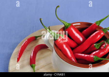 rote Chilischoten in einer Keramikschale auf Holzbrett Stockfoto