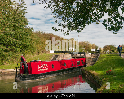 Rot Narrowboat kommen aus einem Schloss und Lockeeper auf Grand Union Canal bei Marsworth, Buckinghamshire, Großbritannien Stockfoto