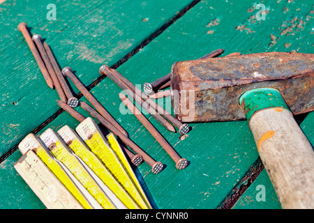 Hammer, Meter und Nägel auf einem grünen Holzbrett Stockfoto