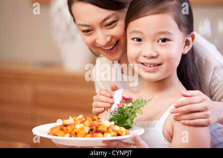 Mutter und Tochter mit einem Teller Kung Pao Chicken, chinesisches Gericht Stockfoto