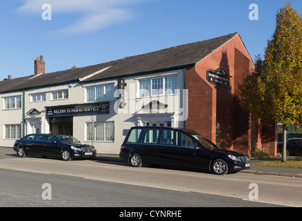 Ein Leichenwagen und eine zusätzliche schwarze Limousine sowohl leer, außen Relphs Trauerfeier an Blackburn Road, Bolton geparkt. Stockfoto