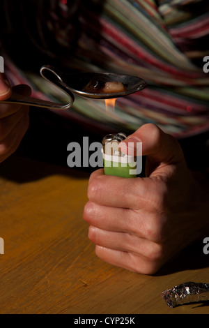 Frau Kochen Heroin in einem gebogenen Löffel Stockfoto