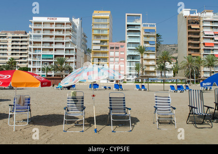 Liegestühle und Sonnenschirme mit den Konstruktionen der spanischen Küste Fonds Stockfoto