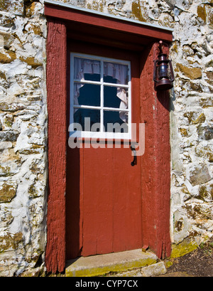 Close up Land Steinhaus rote Farbe Tür und vintage Laterne auf einer Amish Farm, Lancaster County, Pennsylvania, USA, USA, Amerika, pt Winter Stockfoto