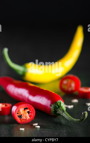 viele farbige Chilis auf dunklem Untergrund angeordnet Stockfoto