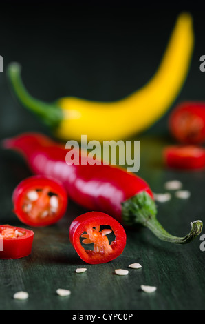 viele farbige Chilis auf dunklem Untergrund angeordnet Stockfoto