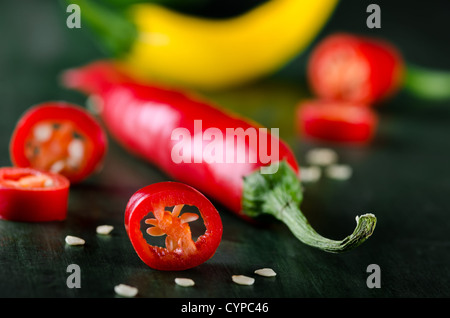 viele farbige Chilis auf dunklem Untergrund angeordnet Stockfoto