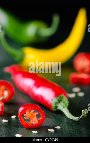 viele farbige Chilis auf dunklem Untergrund angeordnet Stockfoto