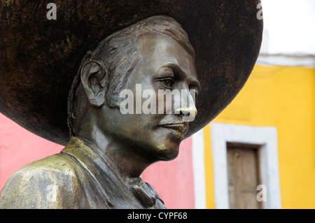 Bronzestatue des Charro Sänger Jorge Negrete mit rosa und gelb gestrichene Gebäudefassade hinter amerikanischen kulturellen Kulturen Stockfoto