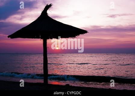 Sonnenschirme an einem einsamen Strand, in den frühen Morgenstunden, bei Sonnenuntergang Stockfoto