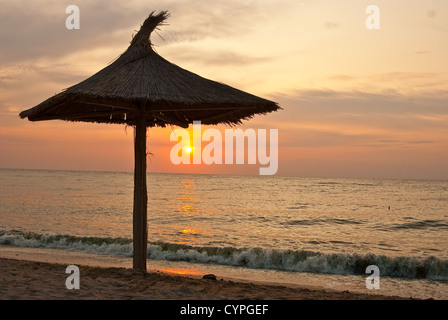 Sonnenschirme an einem einsamen Strand, in den frühen Morgenstunden, bei Sonnenuntergang Stockfoto