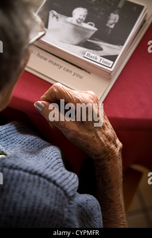 Senior / Oap Dame / Person halten / Blick auf ein Album / Buch von alten Fotografien: Teil der Therapie in einem Altersheim. VEREINIGTES KÖNIGREICH. Stockfoto