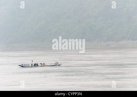 LUANG PRABANG, Laos - eine Sampan übersetzende Personen über den Mekong Fluss an einem nebligen Morgen in der Nähe von Luang Prabang in Laos. Stockfoto