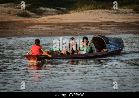 LUANG PRABANG, Laos – Ein kleiner Sampan bringt eine Familie über den Mekong zum Markt von Luang Prabang. Dieses traditionelle Holzboot, das von einem lokalen Bootsmann betrieben wird, dient als wichtiges Transportmittel für Flussgemeinden und verbindet ländliche Gebiete mit dem geschäftigen Marktplatz der UNESCO-Weltkulturerbestätte. Stockfoto