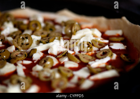 Eine rohe Pizza in den Ofen mit Tomatensauce, Mozzarella-Käse und Oliven bedeckt einsatzbereit Stockfoto