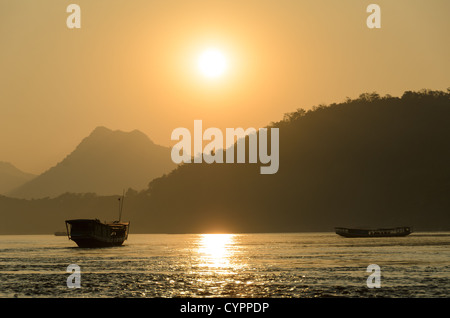 LUANG PRABANG, Laos – Sonnenuntergang auf dem Mekong. Der Mekong fließt in der Nähe der historischen Stadt Luang Prabang im Norden von Laos. Der Fluss, eine der wichtigsten Wasserstraßen Südostasiens, spielt eine entscheidende Rolle in der Ökologie, Wirtschaft und Kultur der Region. Luang Prabang, ein UNESCO-Weltkulturerbe, liegt am Zusammenfluss der Flüsse Mekong und Nam Khan. Stockfoto