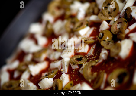 Eine rohe Pizza in den Ofen mit Tomatensauce, Mozzarella-Käse und Oliven bedeckt einsatzbereit Stockfoto