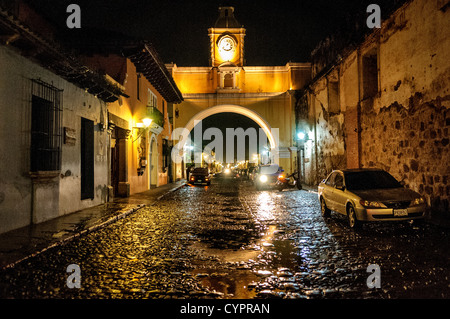 Der Torbogen über die Straße des Klosters Santa Catalina in zentralen Antigua, Guatemala, mit dem Wasser aus den letzten Regen reflektieren das Licht auf der Straße mit Kopfsteinpflaster. Stockfoto