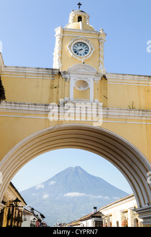 ANTIGUA GUATEMALA, Guatemala – der berühmte Santa Catalina Arch erstreckt sich über die Calle del Arco und bietet einen Blick auf Volcán de Agua in der Ferne. Das gelbe barocke Gebäude mit seinem Uhrenturm und den verwitterten Mauern steht vor dem Hintergrund von kopfsteingepflasterten Straßen und farbenfrohen Gebäuden als Symbol des kolonialen Erbes der Stadt. Stockfoto