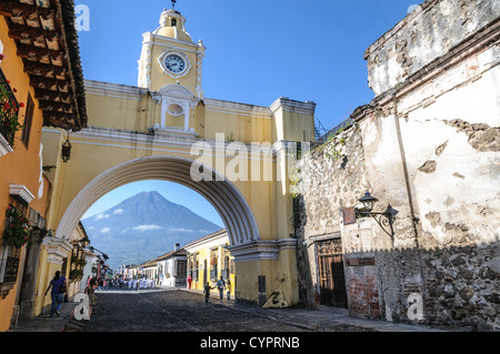 ANTIGUA GUATEMALA, Guatemala – der berühmte Santa Catalina Arch erstreckt sich über die Calle del Arco und bietet einen Blick auf Volcán de Agua in der Ferne. Das gelbe barocke Gebäude mit seinem Uhrenturm und den verwitterten Mauern steht vor dem Hintergrund von kopfsteingepflasterten Straßen und farbenfrohen Gebäuden als Symbol des kolonialen Erbes der Stadt. Stockfoto