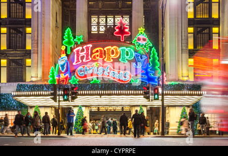 London UK. Weihnachts-Shopper Xmas shopping Selfridge Store Oxford Street mit große Leuchtreklame leuchtet frohe Frohe Weihnachten Stockfoto