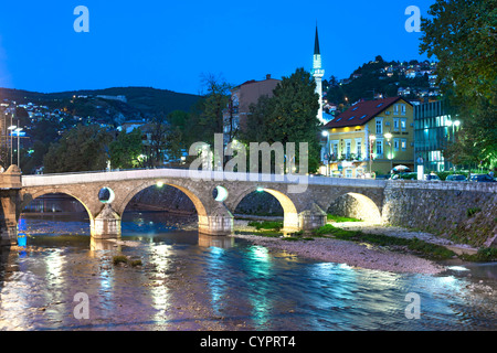 Abenddämmerung Blick auf die Latin Bridge, eine historische osmanische Brücke über den Fluss Miljacka in Sarajevo, Stockfoto