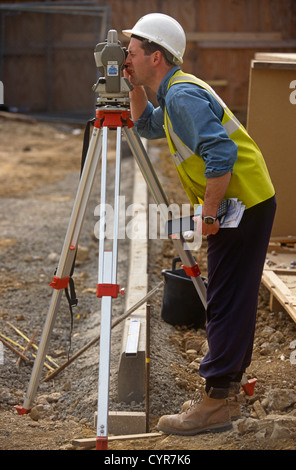 Ein Bauarbeiter verwendet ein Theodolit um Triangulation Winkel an einem Gebäude zu messen Projektwebsite. Stockfoto