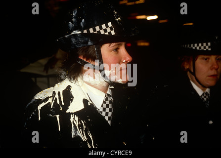 Eine Polizistin (WPC) steht mit weißer Farbe plashed über ihre Uniform bei einem öffentlichen Protest über die Kopfsteuer. Stockfoto