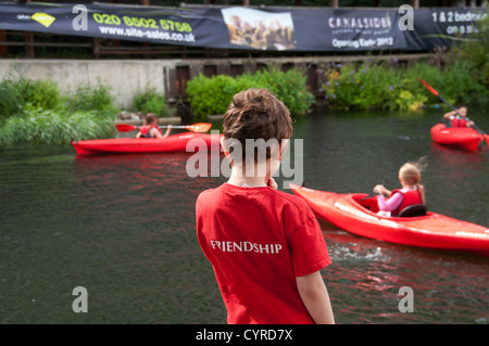 East London. Mile End. Regent es Canal. Junge Mädchen in Kanus und junge beobachten mit Freundschaft, die auf der Rückseite seines Hemdes geschrieben. Stockfoto