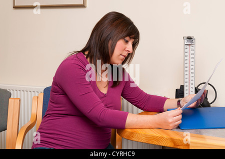 GP-Arzt Chirurgie Patienten schwangere Frau Informationen lesen. Stockfoto