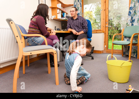Kind spielt mit Spielzeug während ihr Mutter spricht zu den GP-Arzt. Stockfoto